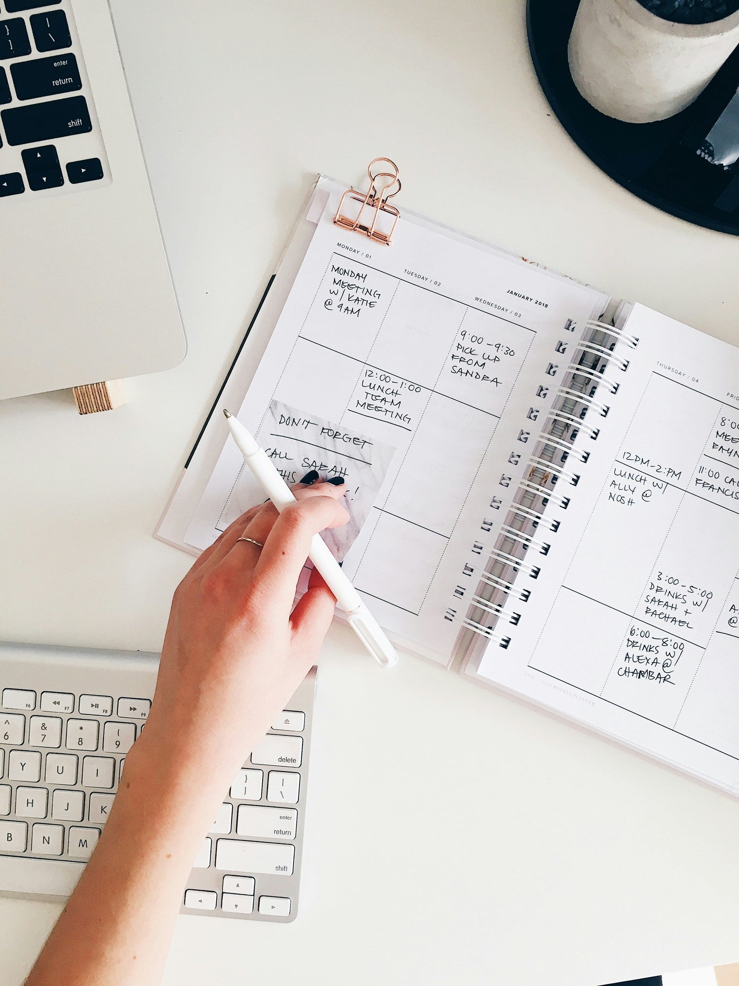 A-hand-placed-upon-a-calender-on-top-of-a-white-office-desk